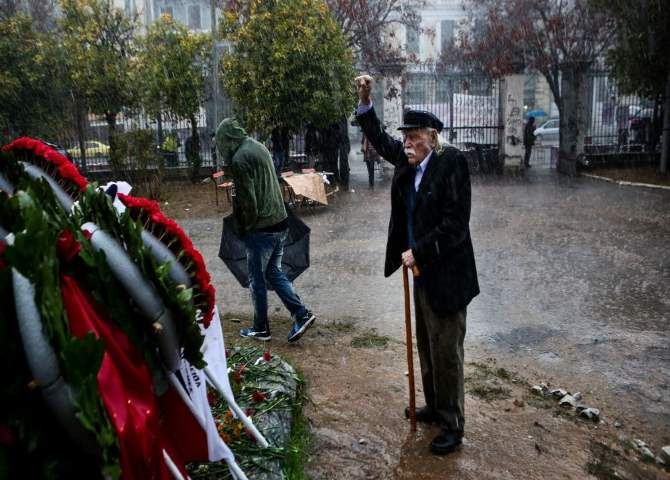 Ο Μανώλης Γλέζος με υψωμένη γροθιά στη βροχή αποτίει φόρο τιμής στους νεκρούς του Πολυτεχνείου